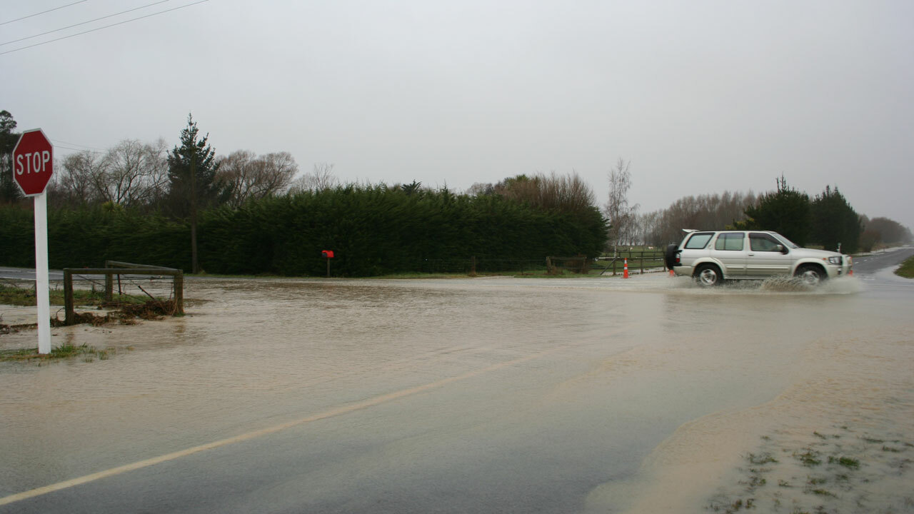 Flooded road intersection with car driving through water
